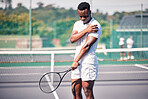 Sports, tennis and arm pain on court after training, game or match outdoors. Healthcare, tennis player and injured black man or athlete with muscle pain or inflammation after exercise or workout.

