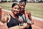 Fitness, selfie and runner girls with medal celebrate winning success at running event at stadium. Sports, friends and support, happy winner women with smile taking picture together on track in sun.