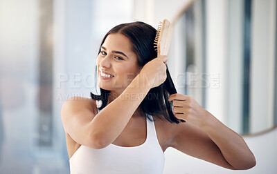 Buy stock photo Hair, brush and bathroom with a woman in her home, brushing her hairstyle for haircare or treatment. Mirror, wellness and luxury with a female using cosmetic shampoo or keratin on her head in a house