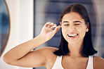 Cotton bud, woman and cleaning ear in bathroom for self care. Personal hygiene, wellness and face of happy, young and comic female from India with tongue out and tool to remove earwax in house alone.