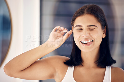 Buy stock photo Cotton bud, woman and cleaning ear in bathroom for self care. Personal hygiene, wellness and face of happy, young and comic female from India with tongue out and tool to remove earwax in house alone.