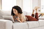 Laptop, ecommerce and customer with a black woman online shopping using her credit card in the house. Computer, living room and payment with a female consumer using technology to shop on the sofa