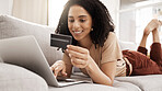 Credit card, laptop and online shopping with a black woman customer lying on a sofa in a living room of her home. Computer, ecommerce and retail with a female consumer spending money on the internet