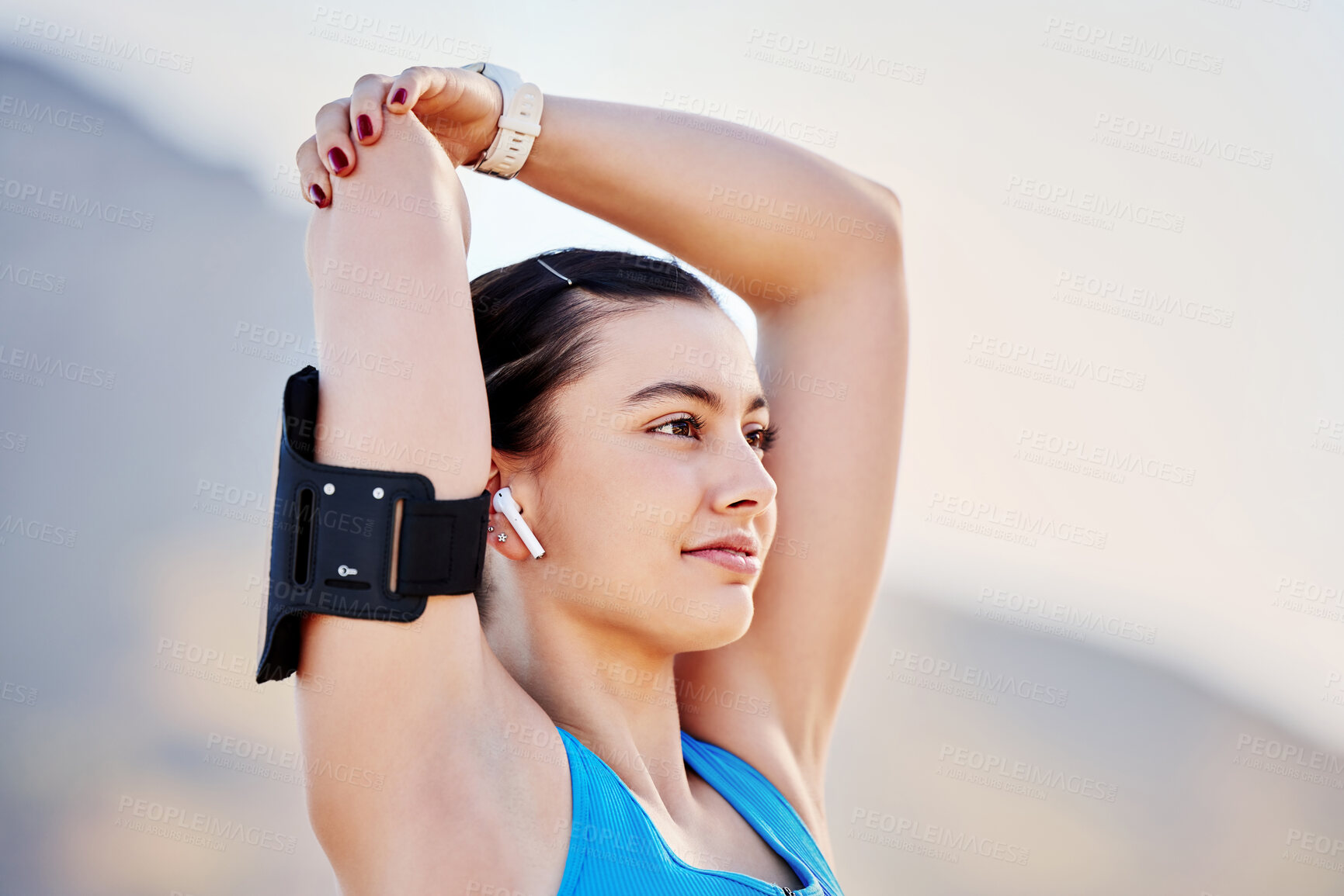 Buy stock photo Young woman, stretching and with arm band for exercise, training and fitness for health and relax outdoor. Healthy female, girl athlete and podcast for balance, calm or wellness for cardio or workout