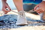 Shoes, running and fitness with a sports woman tying her laces before a cardio or endurance run outdoor. Road, health and exercise with a female runner fastening her shoelaces before a workout