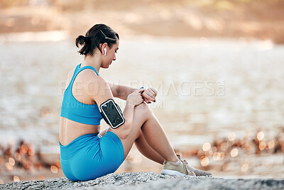 Buy stock photo Fitness, smartwatch time and woman at beach on outdoor technology for exercise results, progress and development check. Runner, sports and athlete with smart watch, cellphone and listening to music