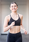 Woman runner, portrait and smile with earphones for music at training, workout or exercise in city. Young athlete girl, happy and running for health, self care or wellness while streaming on internet