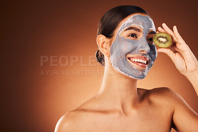 Buy stock photo Face, skincare and woman with clay mask and kiwi in studio on a brown background mockup. Organic cosmetics, fruit and happy female from Canada thinking about healthy facial treatment and nutrition.