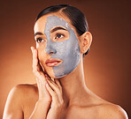 Woman, face skincare and mud mask on orange background in studio self care, dermatology or acne treatment. Beauty model, facial mud and cream product for collagen maintenance, cleaning detox or scrub