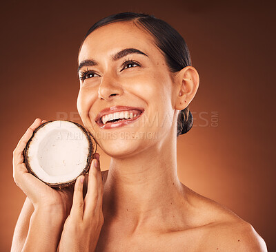 Buy stock photo Coconut, skincare and beauty woman marketing food, thinking wellness and spa facial against a brown studio background. Health, cosmetics and model with a natural oil product for skin glow and detox
