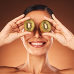 Face beauty, skincare and woman with kiwi in studio isolated on a brown background. Food, cosmetics and happy female model with fruit for healthy diet, wellness or vitamin c, nutrition or facial care