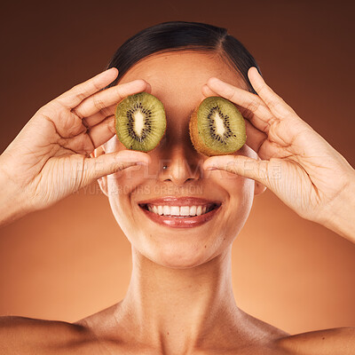 Buy stock photo Face beauty, skincare and woman with kiwi in studio isolated on a brown background. Food, cosmetics and happy female model with fruit for healthy diet, wellness or vitamin c, nutrition or facial care