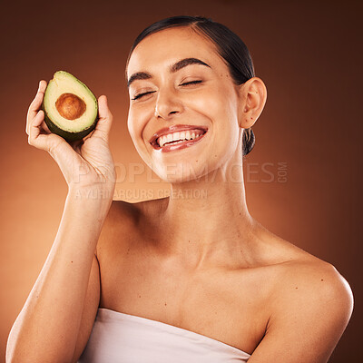 Buy stock photo Face, skincare and avocado with a model woman in studio on a brown background to promote healthy eating. Food, health and wellness with an attractive young female inside for luxury or natural care