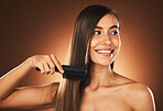 Hair care, happy and woman brushing hair, beauty smile and luxury salon against a brown studio background. Thinking, cosmetic shine and model with hair salon comb and hairdresser styling idea