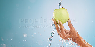 Buy stock photo Water splash, hand of woman and apple in studio on a blue background mockup. Fresh food, cleaning hygiene and female model washing fruit for healthy diet, vitamin c or nutrition, skincare or beauty.
