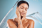 Woman, water splash or skincare cleaning on blue background in studio in healthcare wellness, self care or dermatology wellness. Beauty model, wet or drop motion in brazilian bathroom or relax shower