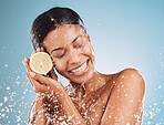 Face, water splash and skincare of woman with lemon in studio isolated on blue background. Cleaning, hygiene and female with eyes closed and healthy citrus fruit for vitamin c, nutrition and wellness