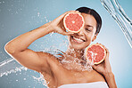 Water, skincare and grapefruit with a model black woman in studio on a blue background for hygiene or hydration. Face, beauty and fruit with an attractive young female posing or cleaning in a shower