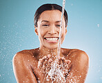 Cleaning, water and black woman with skincare health, beauty wellness and happy shower against blue background in studio. Water splash, cosmetic smile and face portrait of a model with body self care