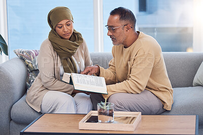 Buy stock photo Muslim couple, bonding and reading book, holy koran or traditional prayer quran on sofa in house or home living room. Islamic man, middle aged woman and mature people in muslim pray for eid mubarak