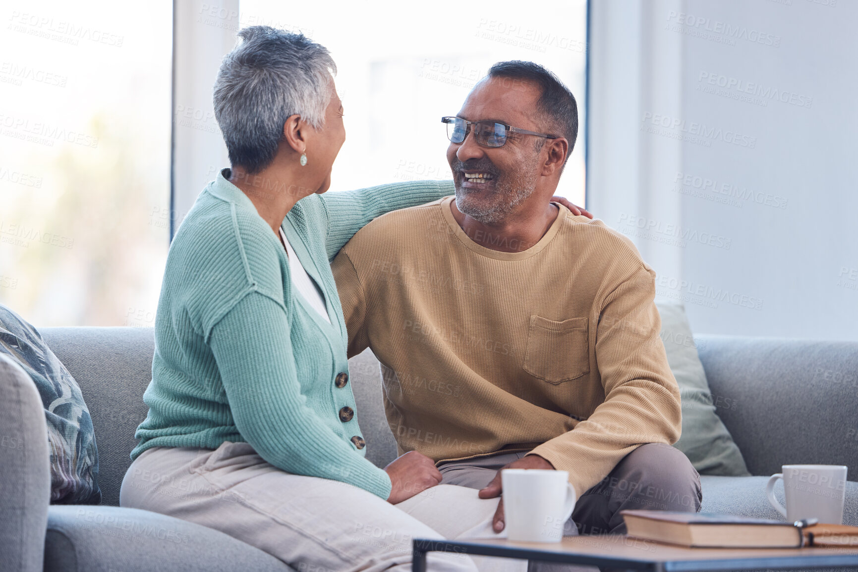 Buy stock photo Elderly couple, smile and hug laughing on sofa or relaxing and bonding time together at home. Happy man and woman relax and enjoying social conversation in love on living room couch at the house