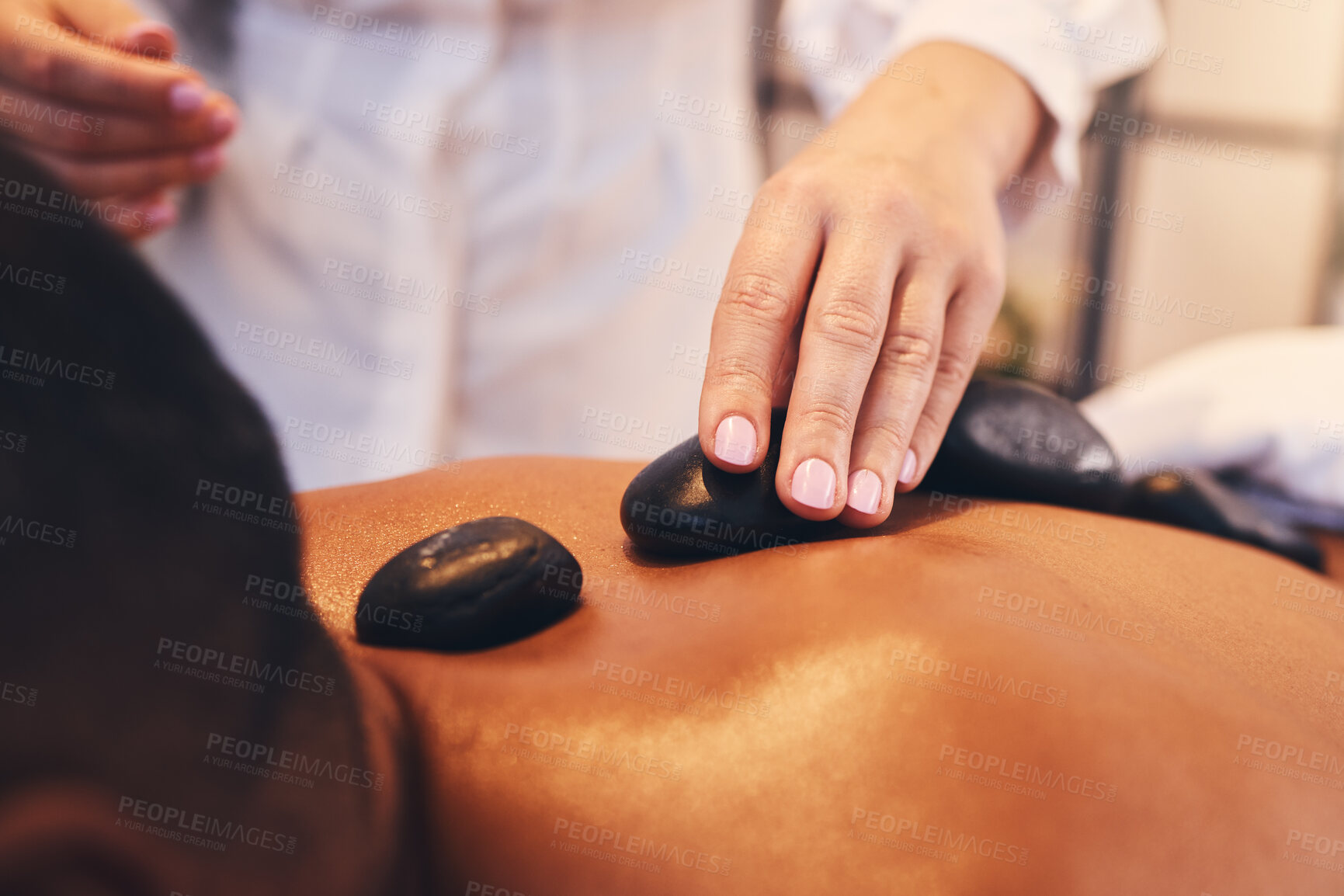 Buy stock photo Hands, hot stone and massage with a man in a spa, lying on a table or bed for stress relief and wellness. Relax, luxury and rock with a male customer in a health salon for physical therapy