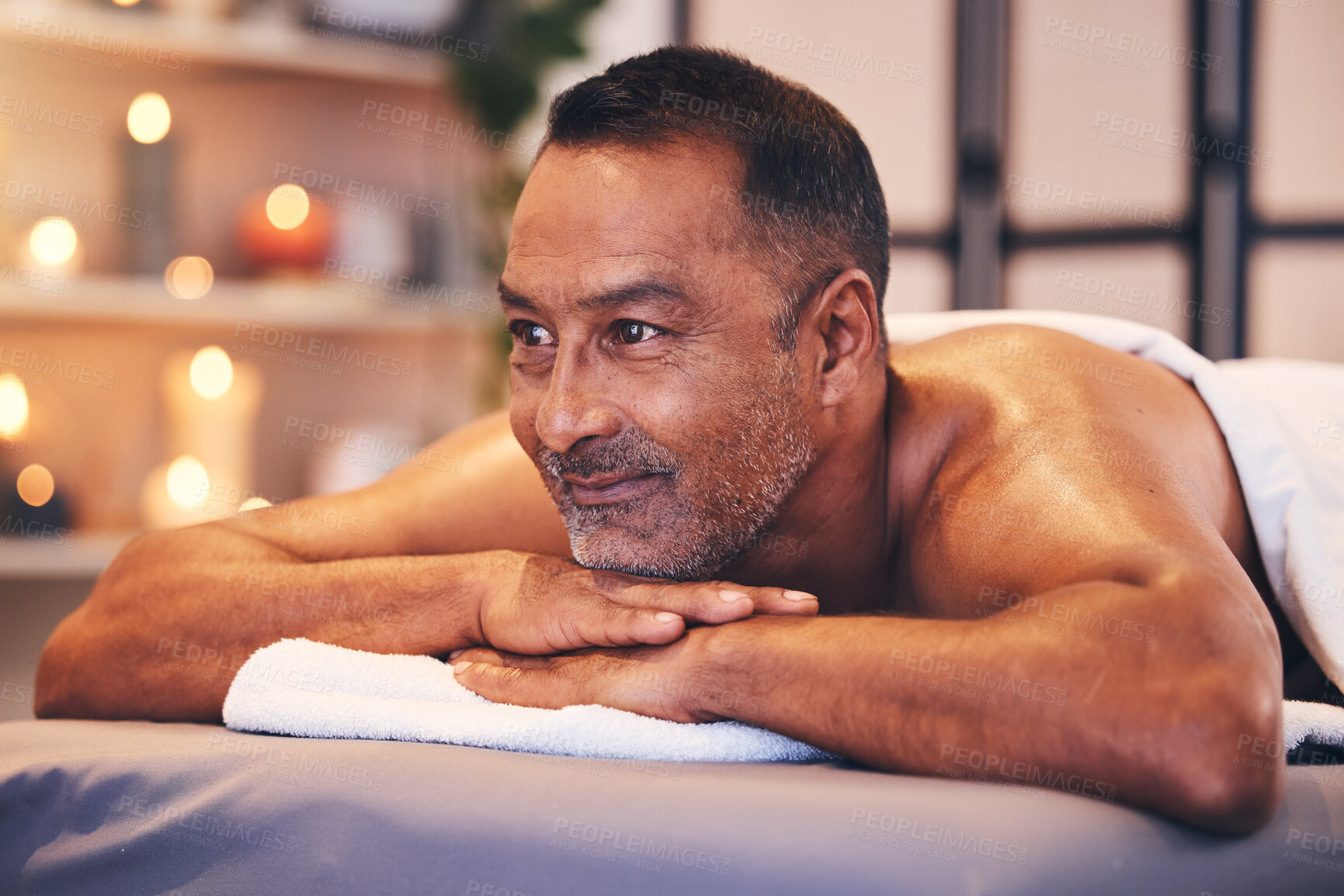Buy stock photo Man, spa massage and table to relax for zen, calm and physical therapy while on vacation for happiness, health and wellness. Face of male thinking about body treatment at beauty salon with a smile