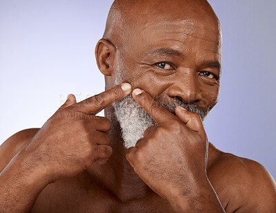 Buy stock photo Face, beauty and skincare with a senior black man checking his skin for a pimple or zit in studio on a purple background. Portrait, wellness and facial cleaning with a mature male posing for hygiene