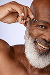 Face, eyebrow tweezers and senior black man in studio isolated on a purple background. Portrait, hygiene and elderly male model plucking eyebrows or hair removal for beauty, wellness and grooming.