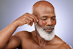 Skincare, eye patches and senior man doing wellness, health and natural face routine in studio. Cosmetic, beauty and elderly African guy doing self care facial treatment isolated by purple background