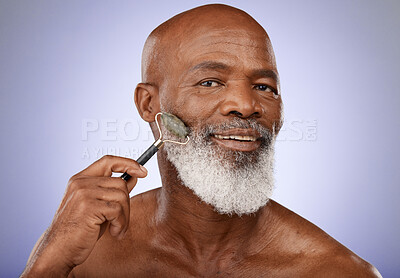 Buy stock photo Skincare, face roller and old man facial massage with gua sha stone for glowing healthy skin. Wellness, dermatology and relax, portrait of black man with jade roller for anti aging routine in studio.