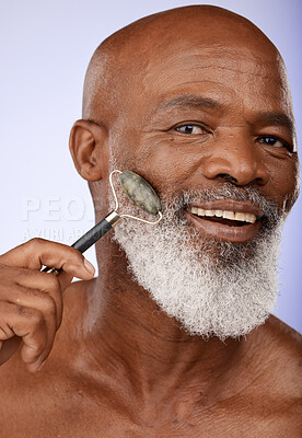 Buy stock photo Skincare, face roller and senior black man in studio on purple background for wellness, beauty and grooming. Dermatology, cosmetics and elderly male with jade roller for facial massage and treatment