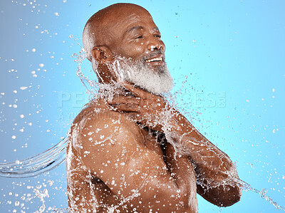 Buy stock photo Beauty, water and cleaning splash of senior man for body care, hygiene and health lifestyle. Happy, shower and mature black model washing skin at studio blue background with satisfied smile.
