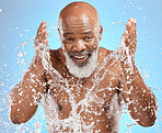 Black man cleaning face, water splash and skincare with beauty, hygiene and facial care in portrait against blue background. Mature model with water, splash and skin hydration, wellness and grooming.