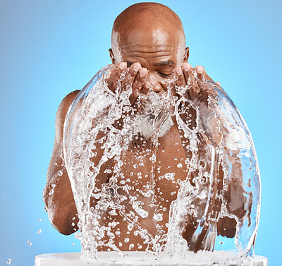 Buy stock photo Water splash, black man and facial skincare on blue background for shower, wellness and clean body care with personal hygiene. Male beauty, studio model and washing face with water drops in bathroom