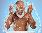 Water splash, skincare and black man in studio for cosmetics, dermatology and facial cleaning in bathroom mockup. Water drops, senior man model for face wash, skin care in morning on blue background 