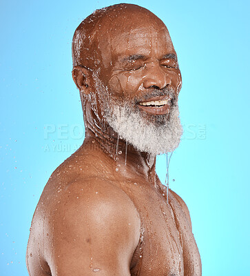 Buy stock photo Water splash, skincare and face of senior black man in studio isolated on a blue background. Cleaning, hygiene and retired elderly male from Nigeria bathing or washing for wellness and healthy skin.