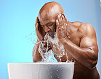 Skincare, water splash and black man for senior skincare while washing face for a glow, healthy and clean skin on blue background. African model in studio with basin for dermatology and self care