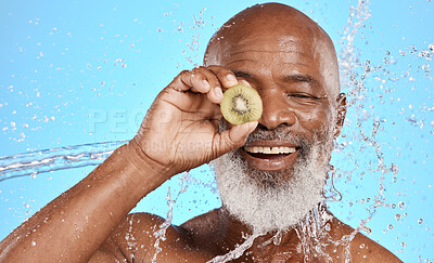 Buy stock photo Skincare, kiwi and senior man in studio for beauty, water splash and wellness on blue background mockup. Beauty splash, fruit and water with elderly man cleaning, happy and relax with nature product