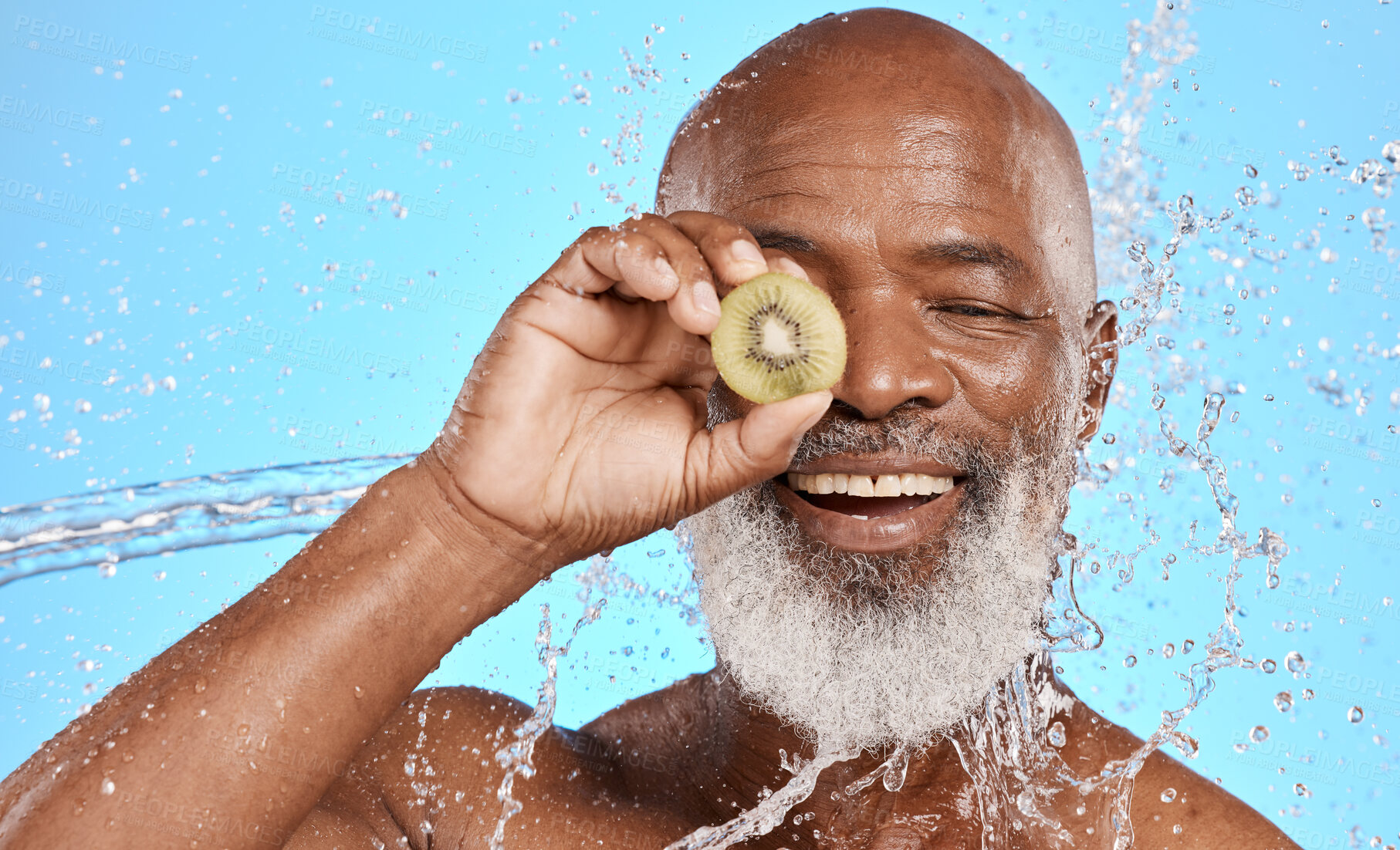 Buy stock photo Skincare, kiwi and senior man in studio for beauty, water splash and wellness on blue background mockup. Beauty splash, fruit and water with elderly man cleaning, happy and relax with nature product