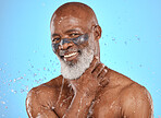 Portrait, facial and senior man in studio for wellness, cleaning and skin mask with water splash on blue background. Face, elderly man and skincare mask, beauty splash and luxury product in shower 