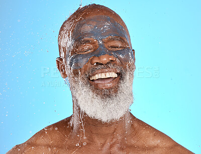 Buy stock photo Face, water splash and senior black man in clay mask in studio isolated on a blue background. Cleaning, retired and elderly male from Nigeria washing off facial cosmetics for skincare or healthy skin