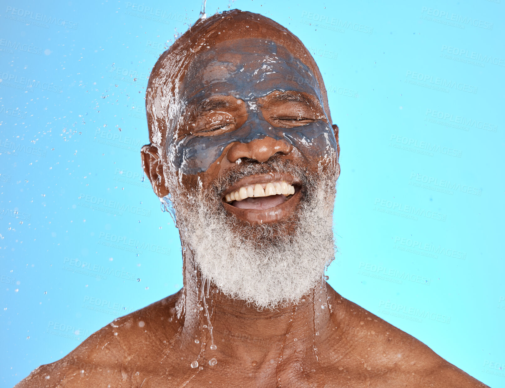 Buy stock photo Face, water splash and senior black man in clay mask in studio isolated on a blue background. Cleaning, retired and elderly male from Nigeria washing off facial cosmetics for skincare or healthy skin