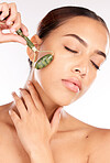 Face, beauty and skincare of woman with jade roller in studio isolated on a white background. Makeup, cosmetics and female model from Canada with eyes closed and facial roller for healthy smooth skin