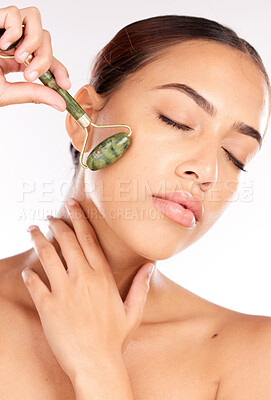 Buy stock photo Face, beauty and skincare of woman with jade roller in studio isolated on a white background. Makeup, cosmetics and female model from Canada with eyes closed and facial roller for healthy smooth skin