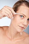 Woman, face and tweezer for beauty, hair removal and epilation on a grey studio background. Aesthetic, hair care and female tweezing her eyebrow for grooming, facial and hygiene treatment 