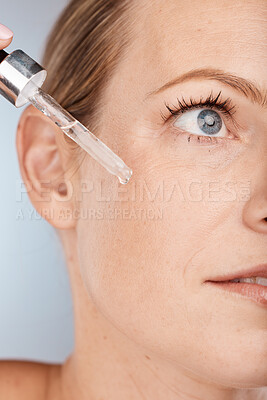 Buy stock photo Face, skincare and serum with a model woman in studio on a gray background to promote a cosmetic product. Facial, beauty and antiaging with a female applying oil to her skin for natural cosmetology