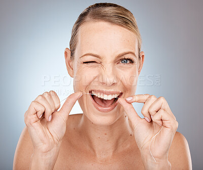 Smile, wink and woman flossing teeth, morning dental care routine on studio background. Health, wellness and happy woman with dental floss, motivation for cleaning a healthy mouth and fresh breath.