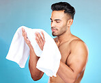 Towel, face and skincare for man, beauty and shower, personal hygiene and grooming cosmetics on studio blue background. Young guy, cotton cloth and facial cleaning for wellness, bath and self care 
