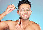 Skincare, health and portrait of man with serum on face for anti aging and glowing skin on blue background. Beauty, facial and male model with smile and collagen oil product in pipette for treatment.